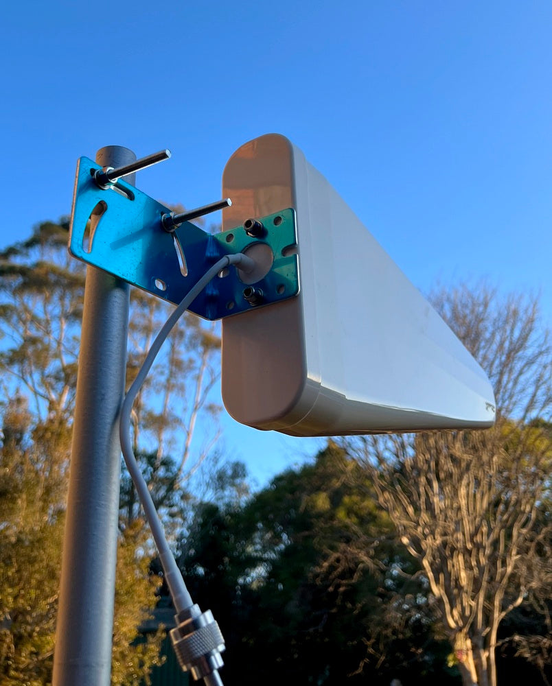 Outdoor antenna mounted on a pole with trees and blue sky in the background