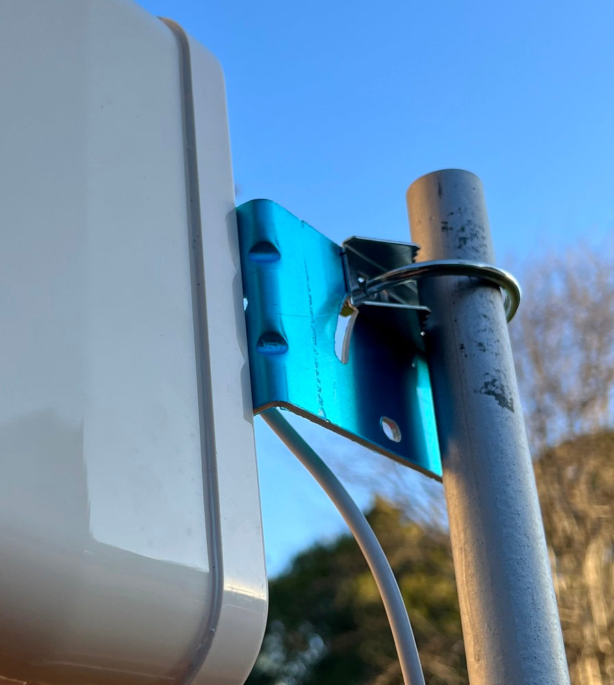 Close-up of a device with a blue connector attached to a metal pole against a blue sky.