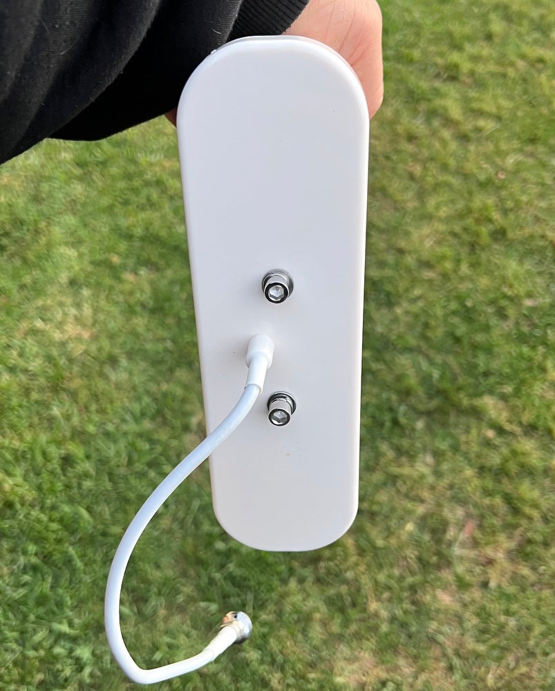 White electronic device with a cable on a grassy background