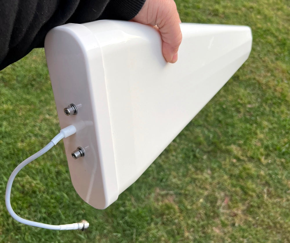 White antenna with a cable held by a person on a grassy background